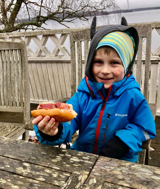 Minstebror äter korv med bröd på altanen