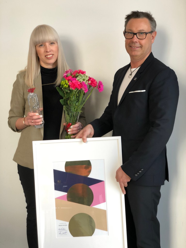 Caroline Axelsson och Roger Pihl med diplomtavla, skulptur och blommor